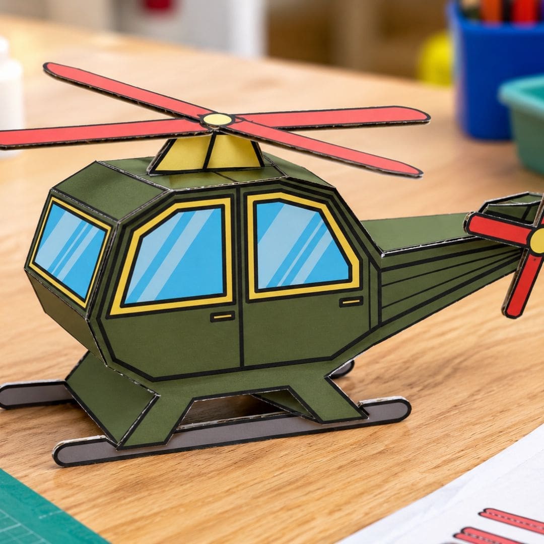 Realistic handmade cardboard helicopter craft assembled on a kids’ workshop table, featuring an army-green body, blue windows, red rotors, yellow details, and gray landing skids.
