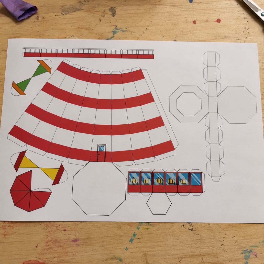 Printable Build a Lighthouse craft sheet placed on a wooden kids’ workshop table with scissors, glue, colored pencils, and craft supplies around it.